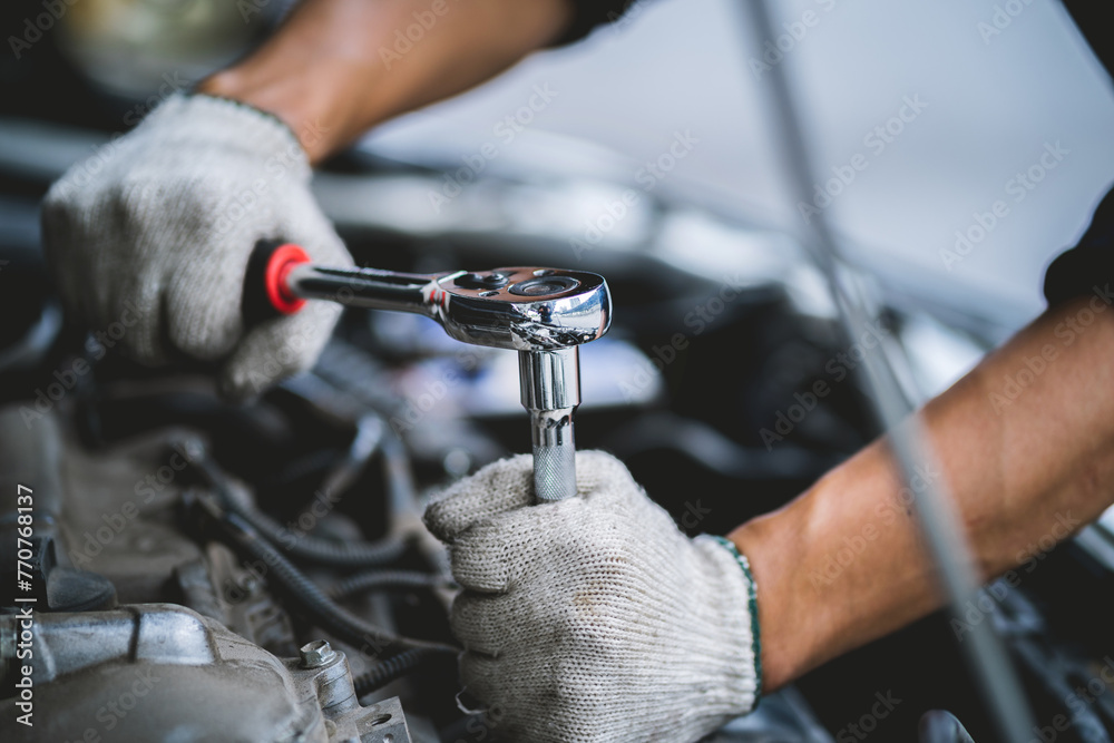 Fototapete A mechanic is working on a car engine, using a socket wrench to loosen a bolt. Concept of focus and determination as the mechanic works to fix the car