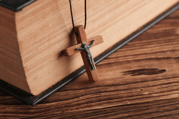 Obraz premium Bible book and wooden Christian cross on a string, wooden table