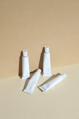 White tubes of acrylic or oil paint on a beige background. Mockup for design