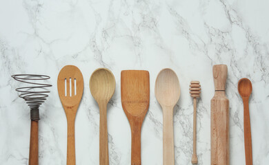 Wooden kitchen utensils on a marble background. Top view. Copy space
