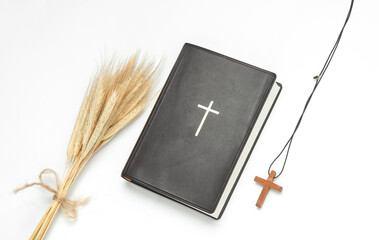 Holy Bible book with ears of wheat and wooden cross on a white background