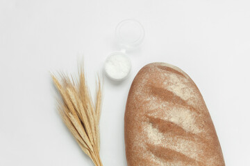 Spikelets of rye and bread with salt on a white background