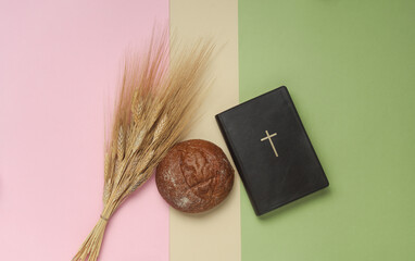 Bible book with bun and wheat grains on pastel background