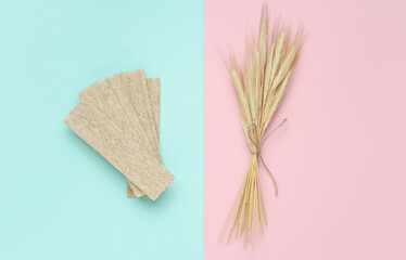Dietary bread with wheat ears in a blue-pink background