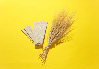 Dietary bread with wheat ears in a yellow background