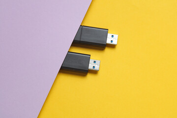 Two black USB flash drives on purple yellow background