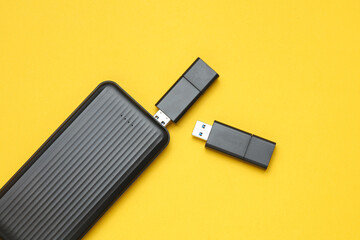 USB flash drives and external hard drive on a yellow background