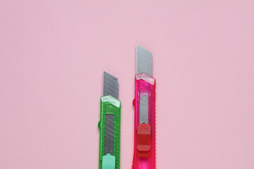 Plastic colored stationery knives for cutting paper on pink background