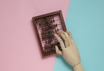 Wooden hand using Abacus on a blue-pink background. Business concept