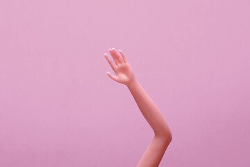 Hand of a doll on a pink background. Creative layout