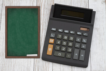  The cost of tuition for education with a black calculator with a chalkboard on wood desk