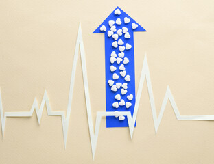 Healthy heart concept. Paper-cut heart rhythm cardiogram with heart-shaped pills and up arrow on a...