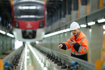 Portrait of a young male technician using a walkie talkie working and standing in a skytrain repair station.