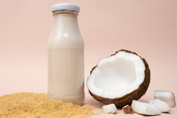 Rice coconut vegan milk in glass bottles on beige background