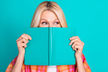 Photo of positive person with blond hair dressed checkered shirt peek from book look empty space isolated on teal color background - obrazy, fototapety, plakaty