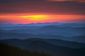 Obraz premium Sunset Spectrum: Layered Mountain Silhouettes Against a Hazy Backdrop of Red, Purple, Blue, Yellow, and Orange