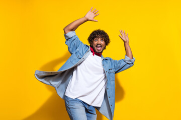 Photo portrait of nice young male raise hands excited dance dressed stylish denim outfit red scarf isolated on yellow color background