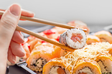 Set of sushi rolls on a white background with bamboo chopsticks and a woman's hand