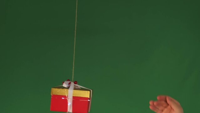 Man's hand sends copter with a red package gift tied to it into flight on a green background. Drone delivering goods. 