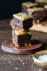 Salted caramel pretzel bottom brownies on a small wooden coaster.
