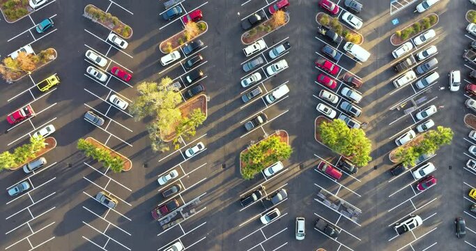 Many parked cars on store parking lot with lines and markings for parking places and directions. Place for vehicles in front of a shopping mall center