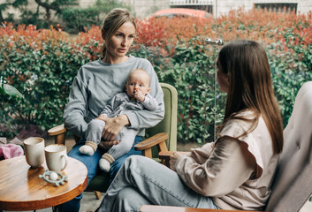 Two young caucasian women are sitting in a cafe with a child.