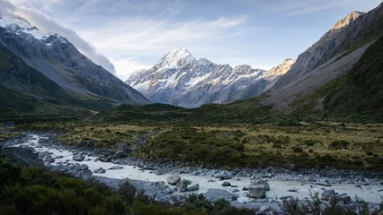 Papier Peint photo Aoraki/Mount Cook Scenic alpine valley with glacial river flowing through and prominent peak in backdrop during sunset