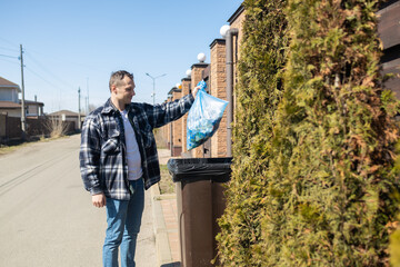 Caucasian man holding garbage blue bag putting in to trash