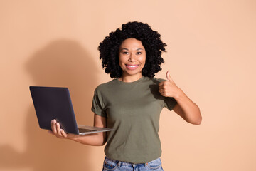 Portrait of multiethnic multinational girl dressed t-shirt hold laptop showing thumb up nice job...