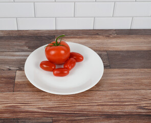 Grouping of garden tomato and four grape tomatoes on white plate