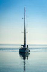Yacht with sails down entering Oakville marina on lake Ontario