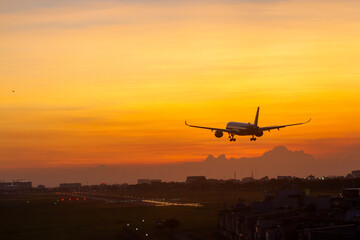 An Commercial Airplane Landing At Sunset.