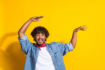 Photo portrait of nice young male raise hands excited dancing dressed stylish denim outfit red scarf isolated on yellow color background