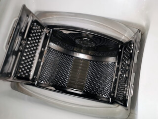 Top view of the open metal drum of a white washing machine with vertical loading for housework to create cleanliness and wash clothes