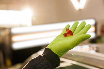 Mechanic with green gloves holds a pin for car dent removal