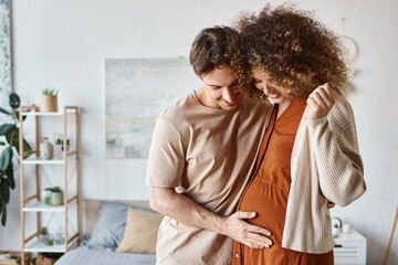 Loving couple in their bedroom, embracing tenderly as they wait for baby, pregnant woman smiling