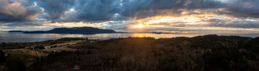 Panoramic aerial sunset over Orcas Island with dramatic clouds. Seen from Lummi Island and looking across Rosario Strait in the San Juan Islands area of western Washington state.  - 770855769