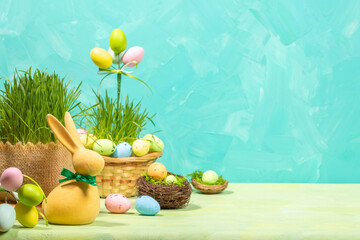 Easter still life. Composition of decorative eggs, yellow bunny, green grass on turquoise Copy space