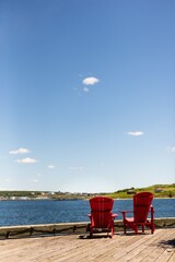 red chairs on dock in front of ocean, peaceful vacation on lake