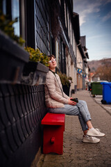 With a thoughtful gaze, a young woman enjoys a peaceful break on a red bench, set against the...