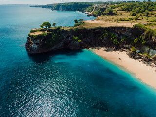 Aerial view of sandy beach with scenic rock and blue sea in Bali