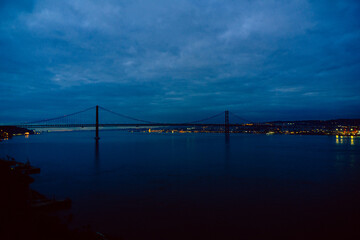 Lisbon April 25 bridge on a cloudy day blue hour and lights on