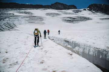 4 mountaineers cross a crevasse in the swiss mountains.