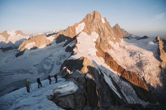 A group of mountaineers walk along a cliff in the mountains.