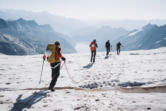 A small group of mountaineers cross over crevasse.