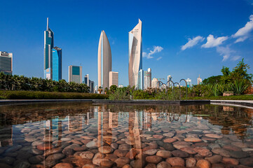 the Al Hamra Tower in Kuwait City photographed from an urban park with a clear pond in the...