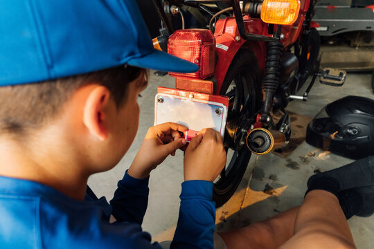 Teenager reapplying a new tag to his moped. 