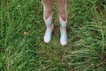 Girl's feet in rainbow rain shoes on the grass
