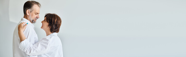 Side view portrait of middle aged couple in love hugging and looking at each other , banner