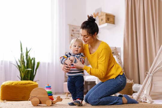 Mother assist son first steps home atmosphere toddler develop